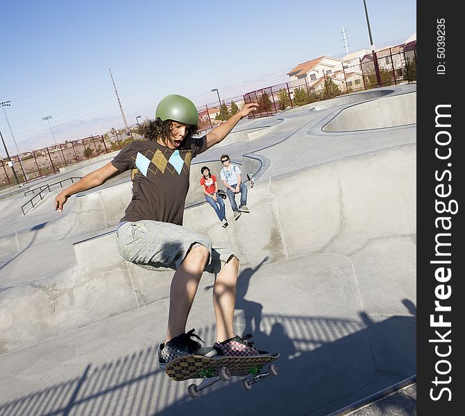 Teen skater does tricks at the skate park with his friends. Teen skater does tricks at the skate park with his friends