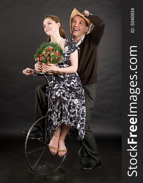 Vintage happy couple on a bicycle over dark background