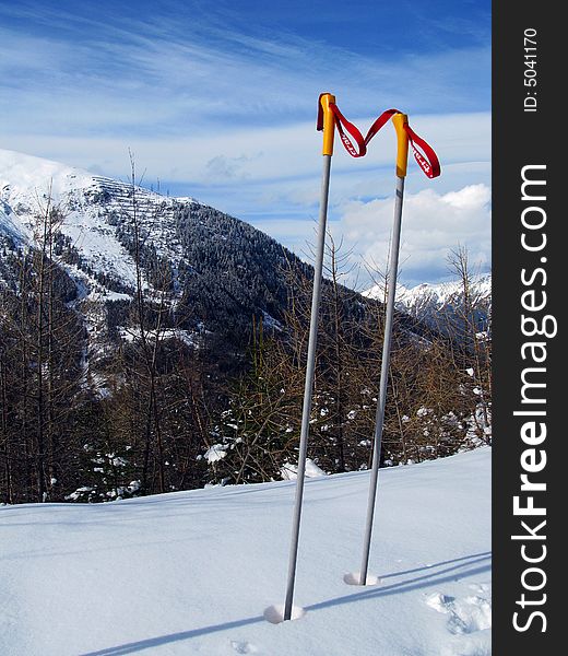 Some Ski Poles on a mountain, resting whilst the skier takes in the view.