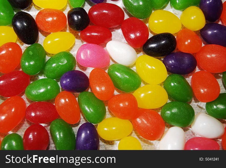 Colorful, tasty jelly beans spread out over a flat surface. The candy is viewed from directly above, and fills the frame entirely with orange, yellow, white, black, pink, green and red. Colorful, tasty jelly beans spread out over a flat surface. The candy is viewed from directly above, and fills the frame entirely with orange, yellow, white, black, pink, green and red.