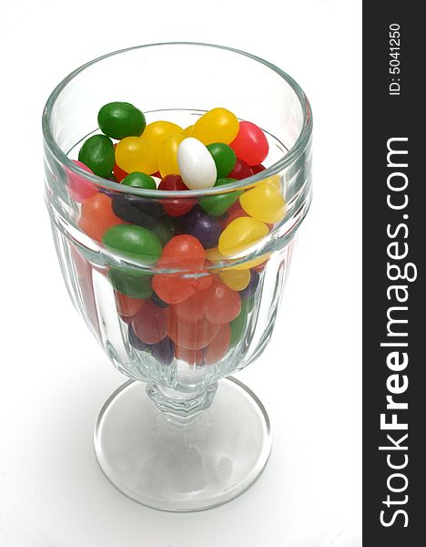 A glass sundae cup mostly filled with colorful jelly beans. The view is from slightly above, vertically oriented over white. A glass sundae cup mostly filled with colorful jelly beans. The view is from slightly above, vertically oriented over white.
