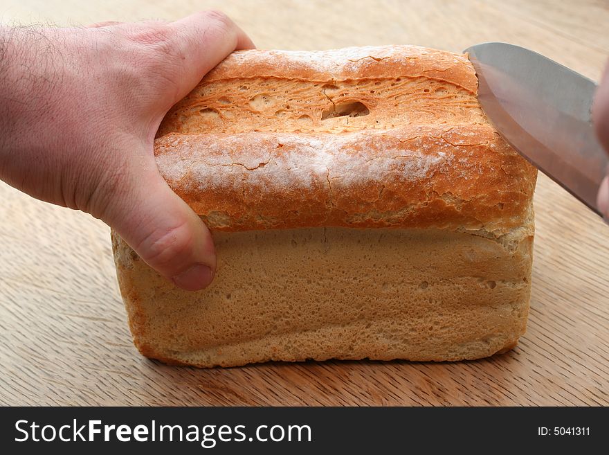 Cutting into a golden loaf of freshly cut bread. Cutting into a golden loaf of freshly cut bread