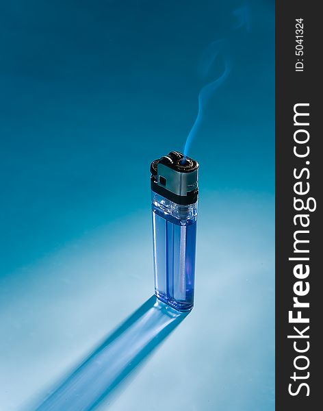 The fuming cigarette lighter on blue with back light