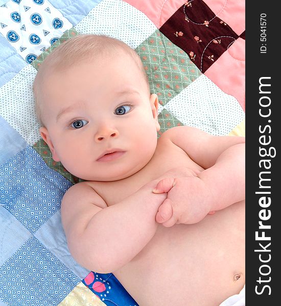 Cute baby lying on back on a multicolored quilt. Cute baby lying on back on a multicolored quilt