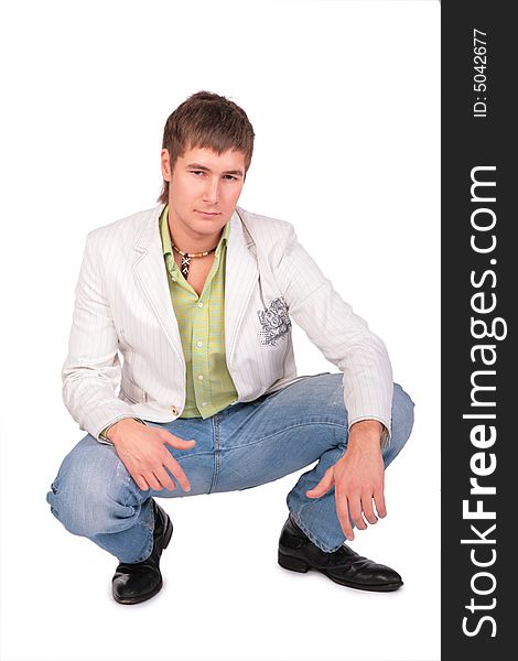 Serious young man sits on white