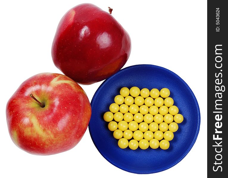 Blue plateful of yellow drops vitamin and red apples above them. isolated on white