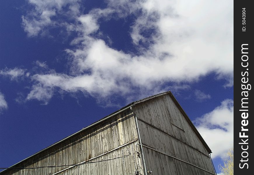 An old wooden barn against a blue sky with white fluffy clouds. An old wooden barn against a blue sky with white fluffy clouds.