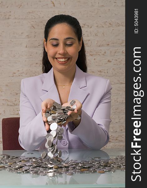 A close-up shot of businesswoman pouring coins out of her hands on to a desk. A close-up shot of businesswoman pouring coins out of her hands on to a desk.