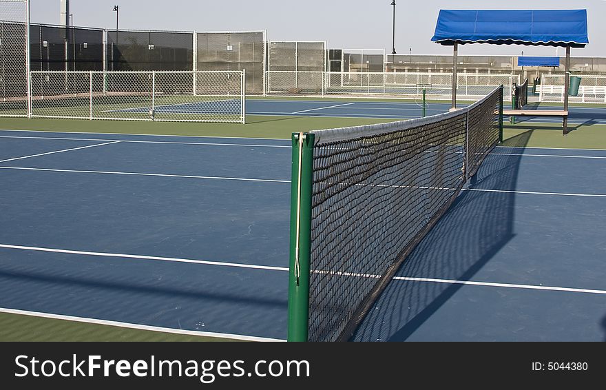 Tennis court net viewed from one end with bench. Tennis court net viewed from one end with bench