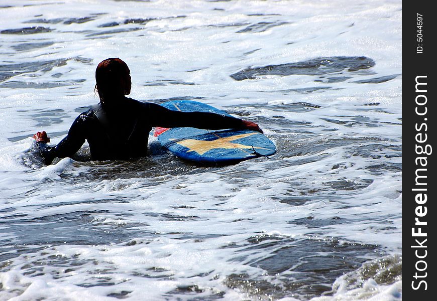 A surfer with his surf is waiting for the right wave. A surfer with his surf is waiting for the right wave