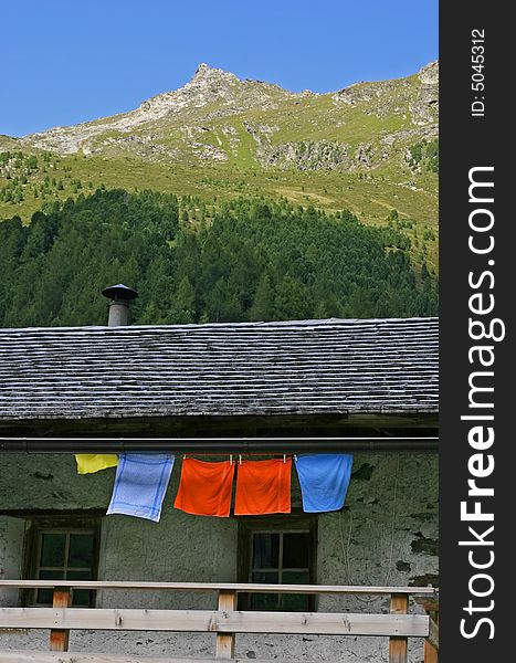Alpine scenery with hut, mountain and colorful textiles