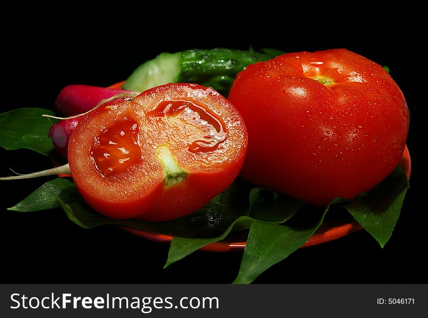 Fresh vegetables on a plate on a black background. Fresh vegetables on a plate on a black background