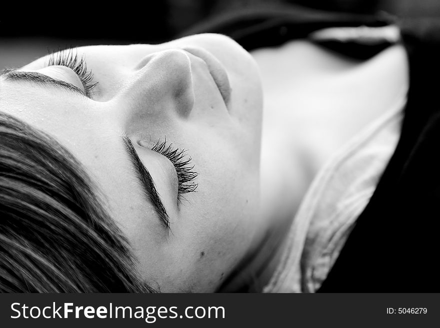 Laying woman with closed eyes, black and white.