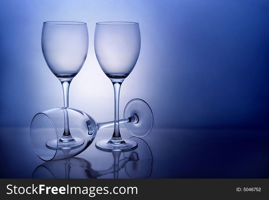 Three empty wine glasses on blue background