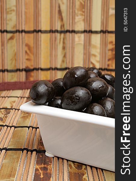 Olives in white plate on a mat