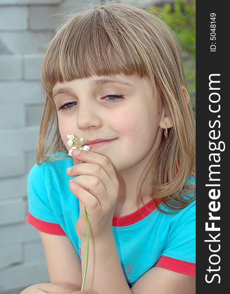 Little pretty girl with lilies on the background of white bricks. Little pretty girl with lilies on the background of white bricks