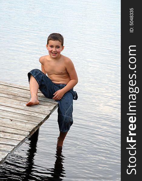 Smiling boy sitting on the river pier. Smiling boy sitting on the river pier