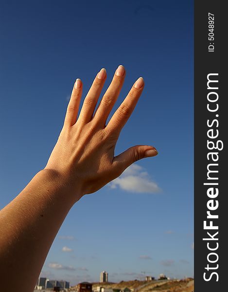 Female hand on blue sky background