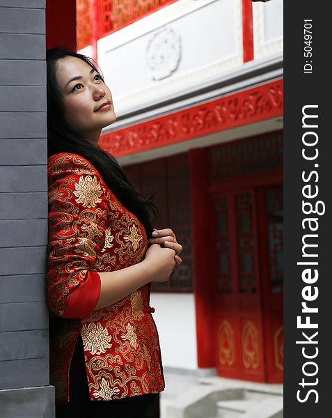 A Chinese girl in traditional dress stands at the front door of the ancient courtyard of China. Perhaps she is longing for the future. A Chinese girl in traditional dress stands at the front door of the ancient courtyard of China. Perhaps she is longing for the future.