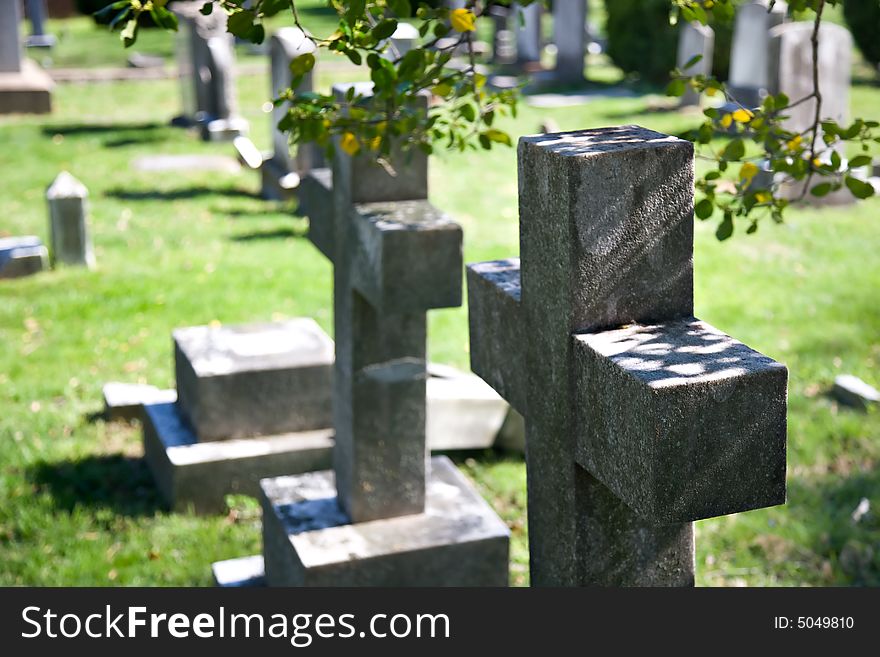 Granite stone crosses mark graves in an old country cemetery. Granite stone crosses mark graves in an old country cemetery.