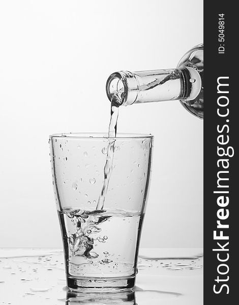 Glass of pouring water with reflection (white background). Glass of pouring water with reflection (white background)