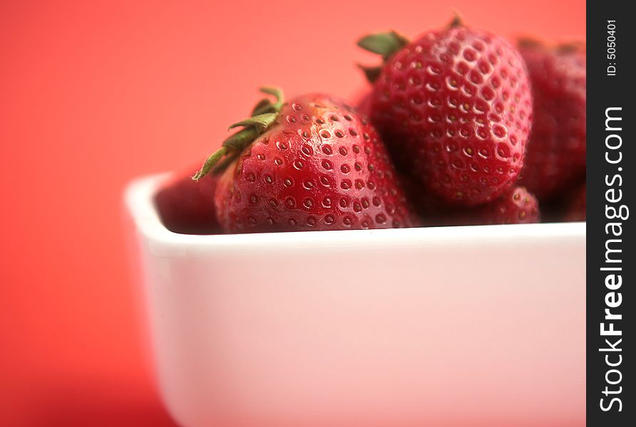 Ripe strawberries in white porceline with red background. Ripe strawberries in white porceline with red background