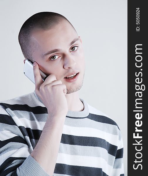 Young man talking by phone at white background
