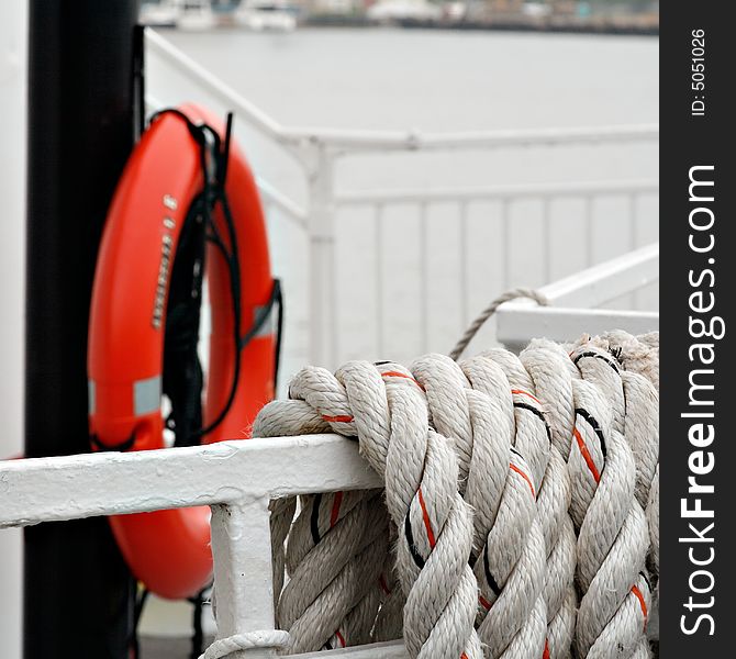 Strands of rope with life preserver in background on a river boat bow.