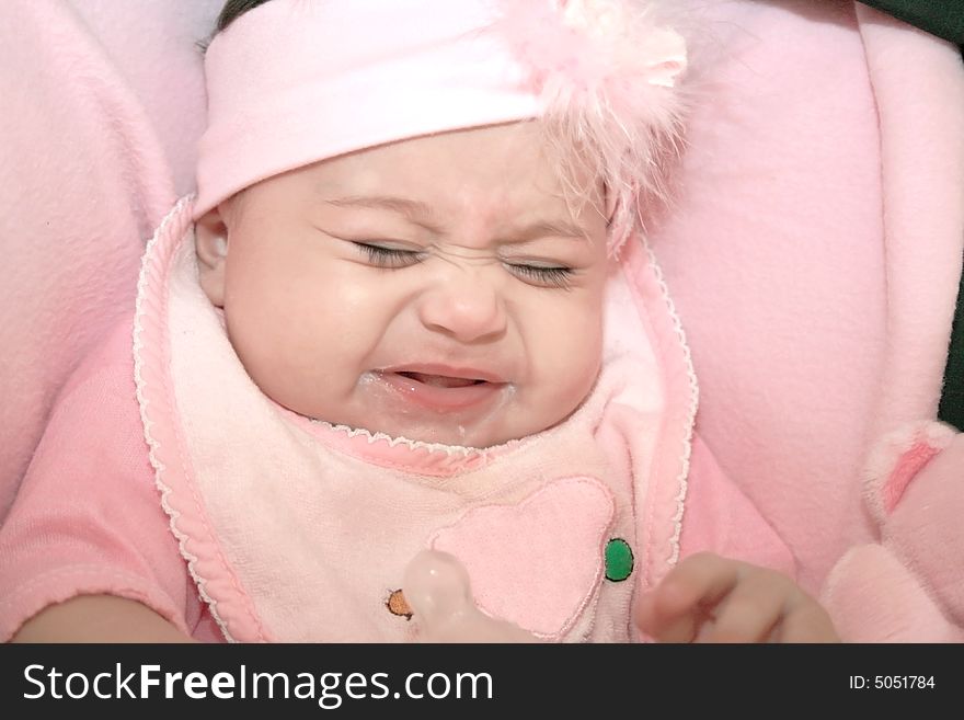 Pretty crying baby girl in pink with dummy.