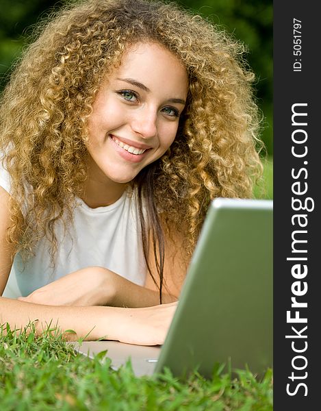 A beautiful young woman using a portable computer outside. A beautiful young woman using a portable computer outside