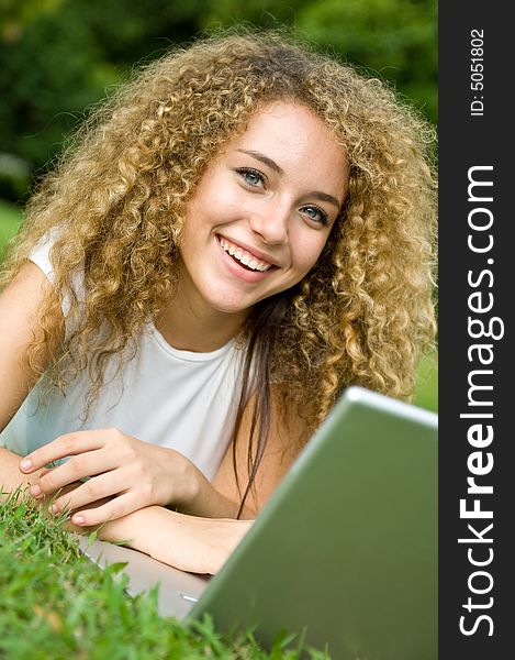 A beautiful young woman using a portable computer outside. A beautiful young woman using a portable computer outside