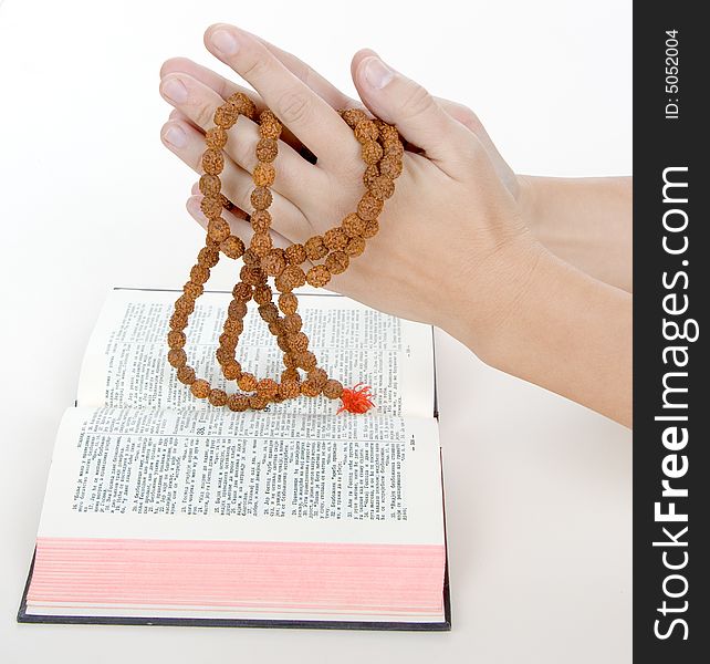 Praying with a rosary over a holy bible, background is white