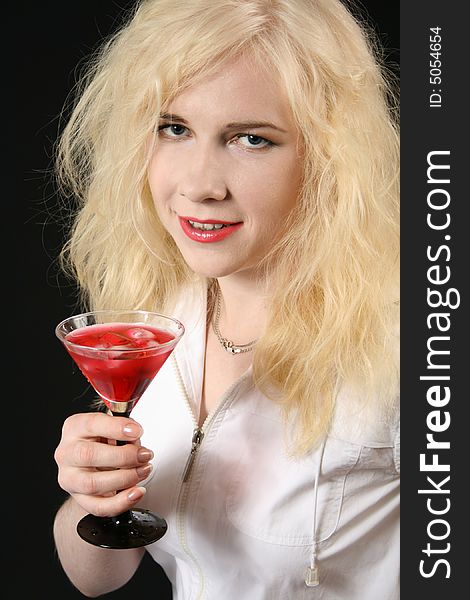 Young blond woman holds martini against the black background. Young blond woman holds martini against the black background