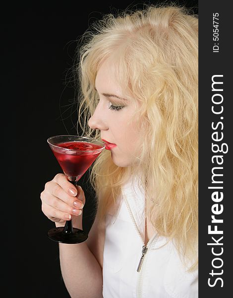 Young blond woman holds martini against the black background. Young blond woman holds martini against the black background