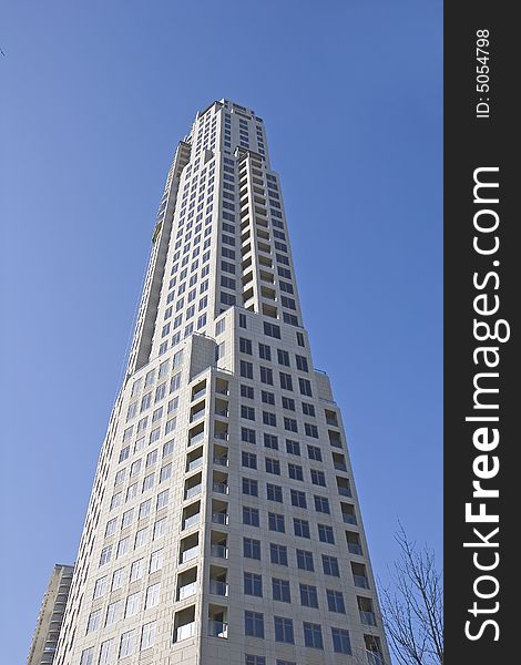 A new modern concrete office tower rising into the blue sky. A new modern concrete office tower rising into the blue sky