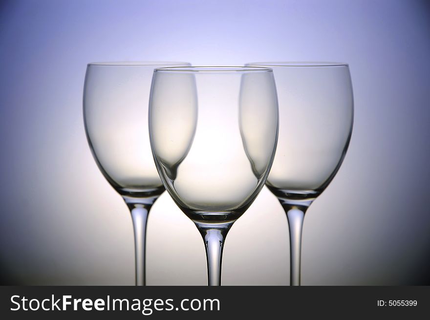 Three empty wine glasses on color background