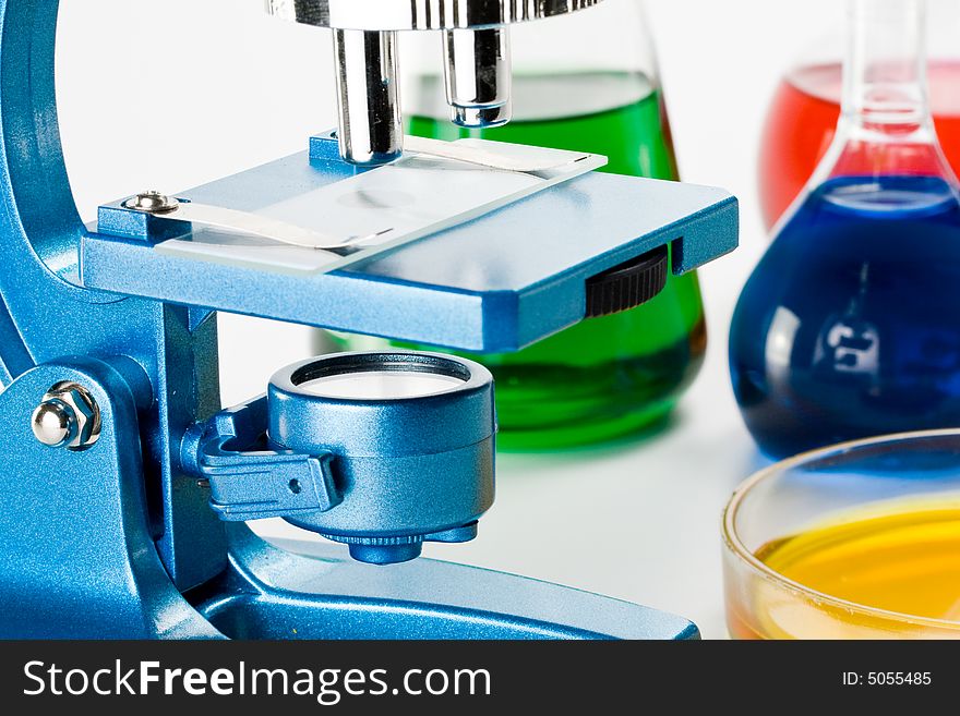 Various colorful flasks and blue microscope over white background