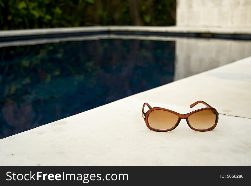 Sunglasses / shades by the poolside. Sunglasses / shades by the poolside.