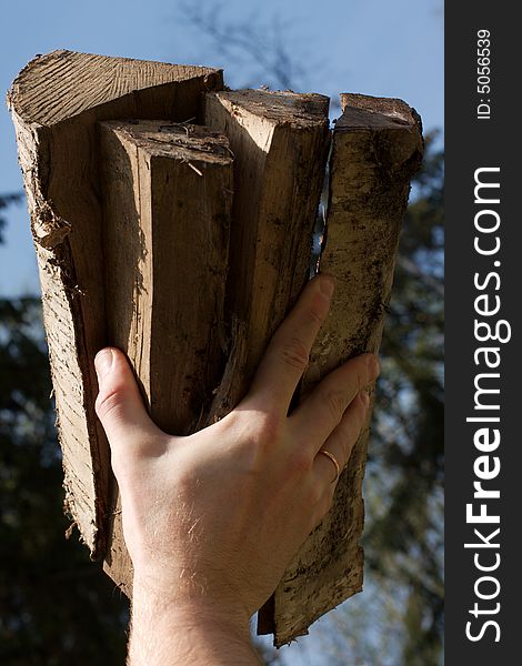 Low angle view of firewood in one hand. Low angle view of firewood in one hand