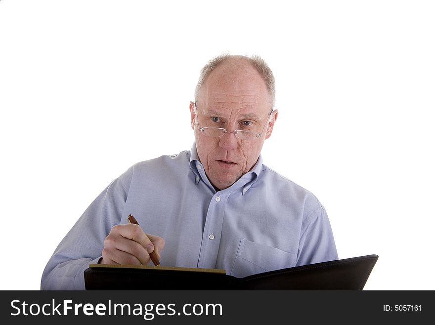 An older man in a blue dress shirt isolated on white taking notes in a black notebook or giving a lecture. An older man in a blue dress shirt isolated on white taking notes in a black notebook or giving a lecture