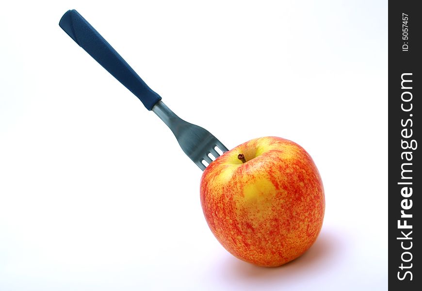 A fork stuck in a fresh red apple on white background. A fork stuck in a fresh red apple on white background