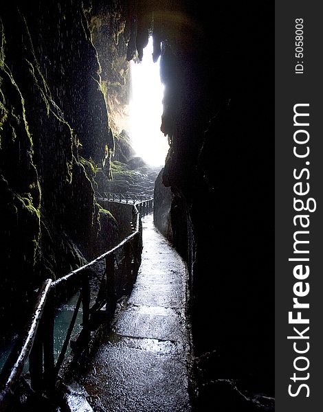 Stone path inside a grot with a wood balustrade and raining. Stone path inside a grot with a wood balustrade and raining