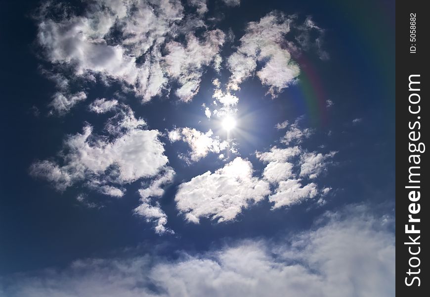 Deep blue sky with sun flare and clouds