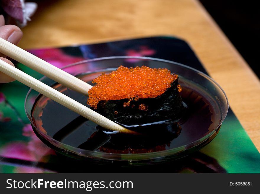 Sushi with red caviar taken with chopsticks