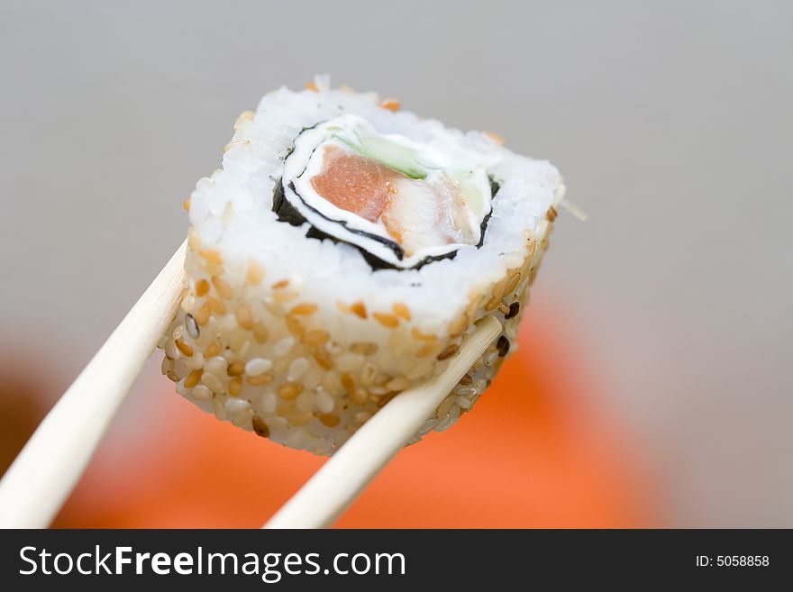 Japanese roll with sesame taken with sticks