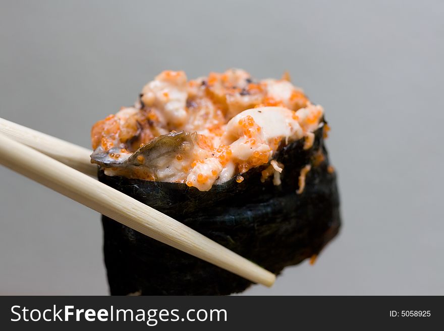 Sushi with chicken taken with chopsticks on gray background. Sushi with chicken taken with chopsticks on gray background