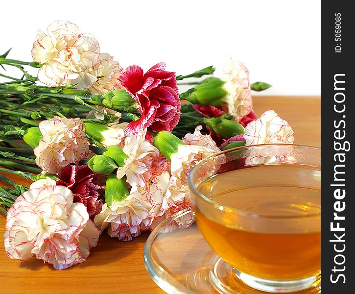 Cup of tea and bouquet of carnations isolated on a white background