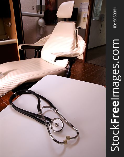 A stethoscope on a white table with medical dentists chair in background. A stethoscope on a white table with medical dentists chair in background.