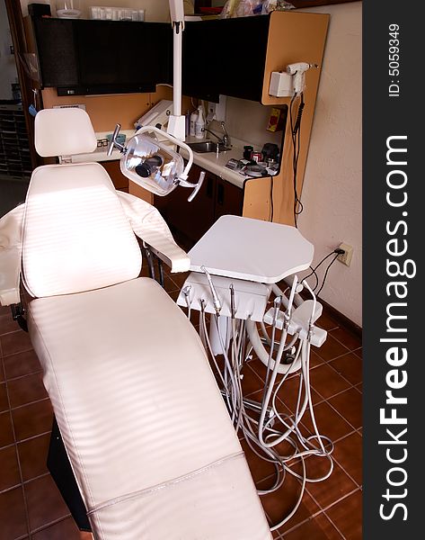 A white dental reclining chair at a dentists office . A white dental reclining chair at a dentists office .