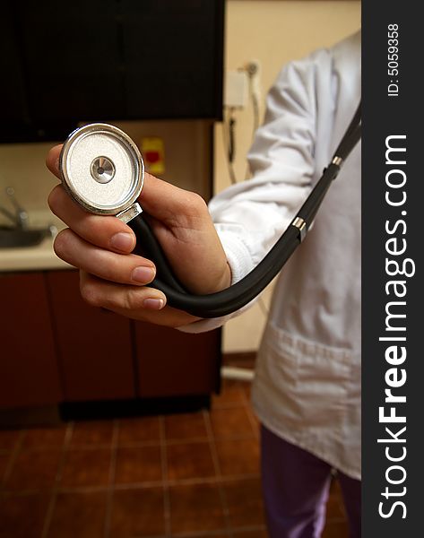 A stethoscope being held up to the camera lens being held by a female doctor in white lab coat. A stethoscope being held up to the camera lens being held by a female doctor in white lab coat.